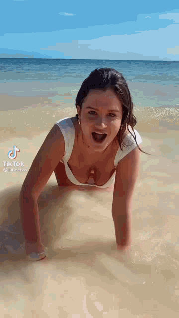 a woman in a bikini is doing push ups in the water on the beach .