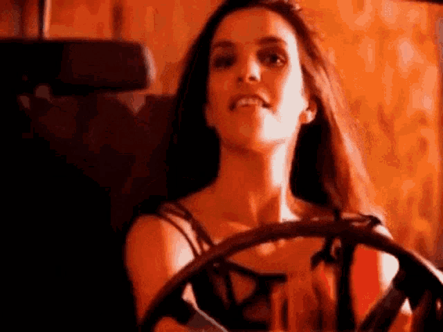 a woman is sitting in the driver 's seat of a car holding a steering wheel .