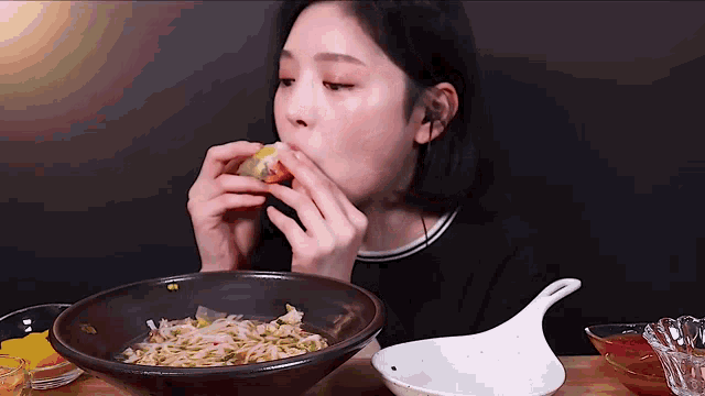 a woman is eating noodles from a bowl with a spoon in it .