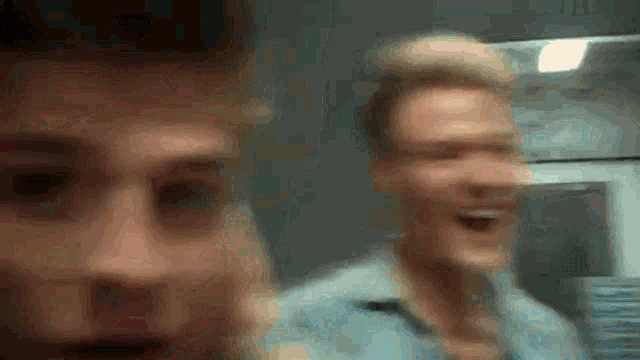a blurry picture of two men laughing and one is looking at the camera