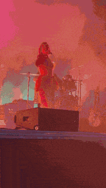 a woman in a pink dress is holding a microphone on stage