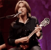 a man is singing into a microphone while holding a guitar