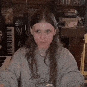 a woman with long hair is making a funny face in front of a piano .