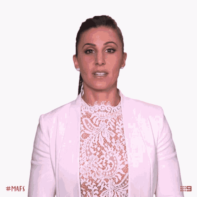 a woman wearing a white jacket and a white lace top is making a gesture