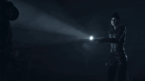 a person holding a flashlight in the dark