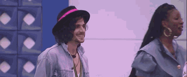 a man wearing a hat and a woman wearing earrings are standing next to each other in a room .