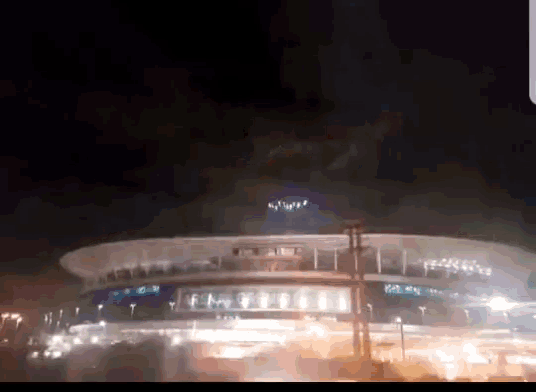 a large building is lit up at night with a fireworks display in the sky