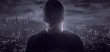 daredevil is wearing a red mask and standing in front of a city skyline .