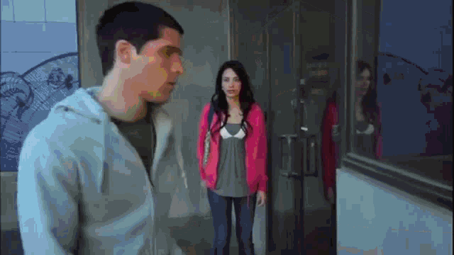 a man and a woman are standing next to each other in front of a door that says ' emergency exit '