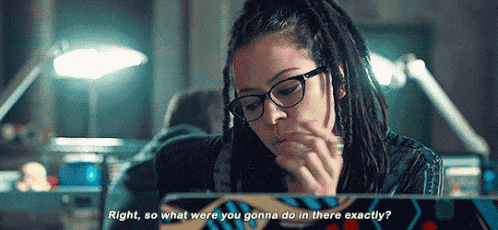 a woman with dreadlocks and glasses is sitting in front of a laptop computer and smoking a cigarette .