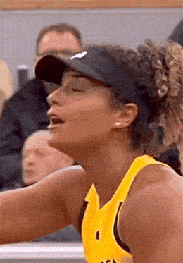 a close up of a woman wearing a hat and a yellow shirt with the number 1 on it