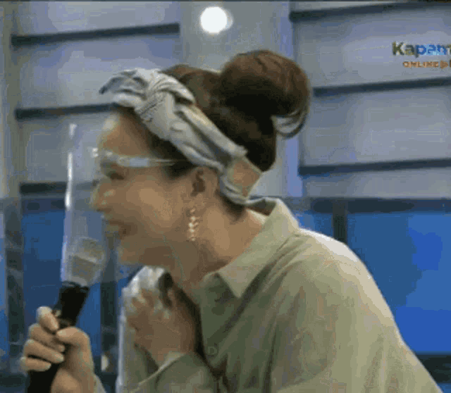 a woman wearing a headband is holding a microphone in front of a screen that says kapamilya online