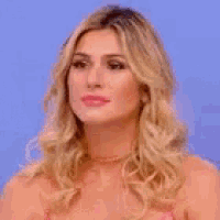 a close up of a woman 's face with blonde hair and a pink top .