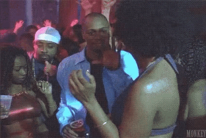 a man is dancing with a woman in a club while holding a cup of beer .