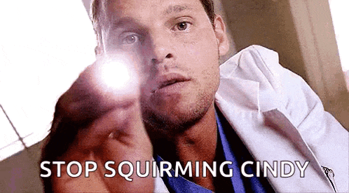 a man in a lab coat is pointing a flashlight at someone .