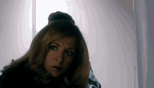 a woman with blonde hair is looking at the camera with a serious look on her face