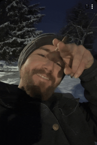a man with a beard is smoking a cigar and smiling in the snow