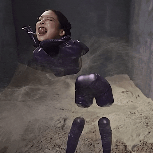 a woman in a purple suit is laying in the sand