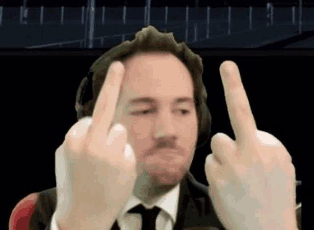 the man is wearing headphones and giving the middle finger .