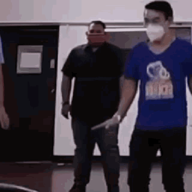 a group of men wearing face masks and gloves are standing next to each other .