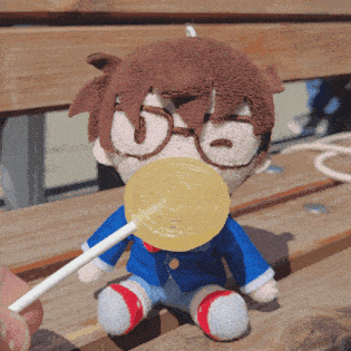 a stuffed toy with glasses is holding a lollipop in its mouth