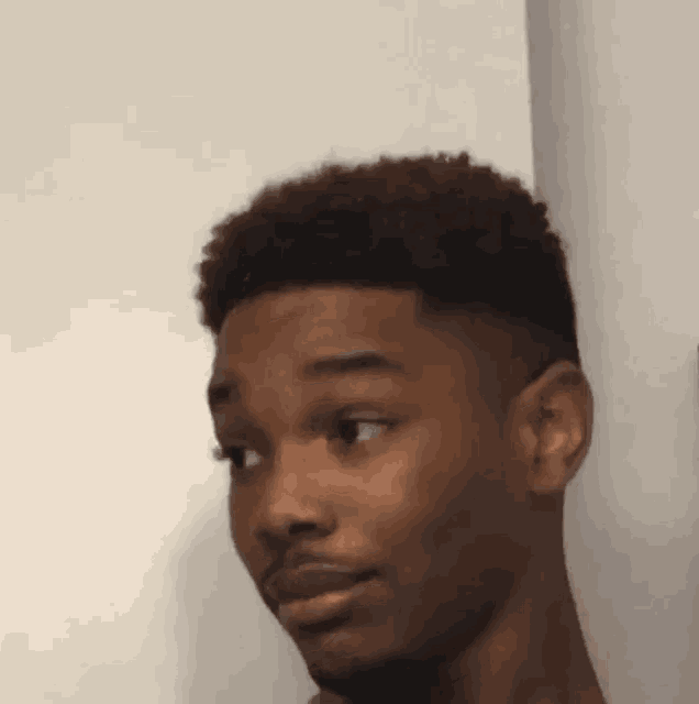 a close up of a man 's face against a white wall making a funny face .