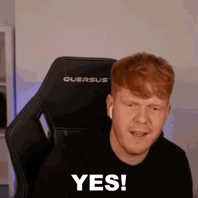 a man with red hair and a beard is sitting in a gaming chair and says yes .