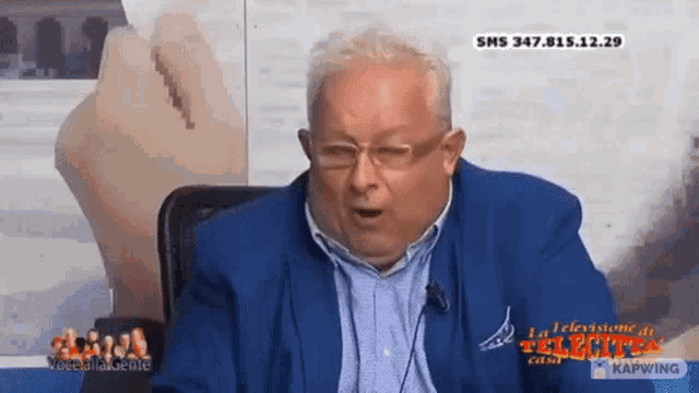 a man wearing glasses and a blue jacket is talking on a television show