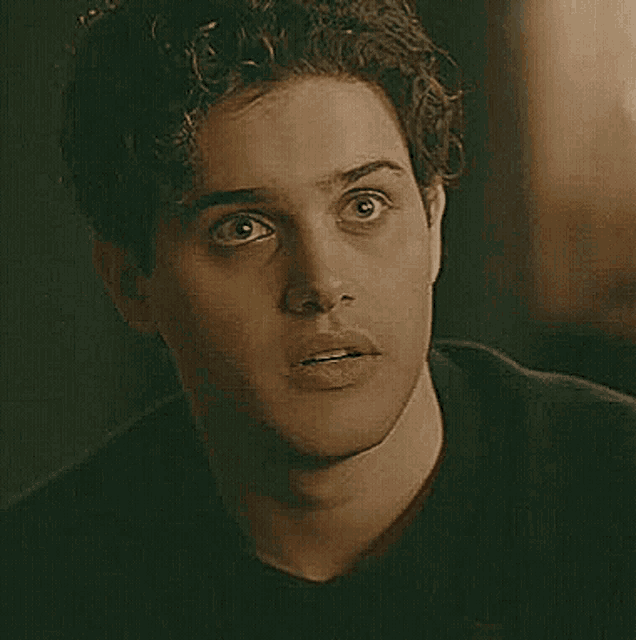 a close up of a man 's face with curly hair looking at the camera .