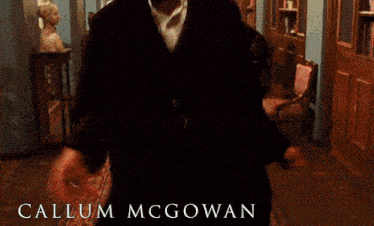 a man wearing headphones is standing in a hallway with the name callum mcgowan on the bottom right