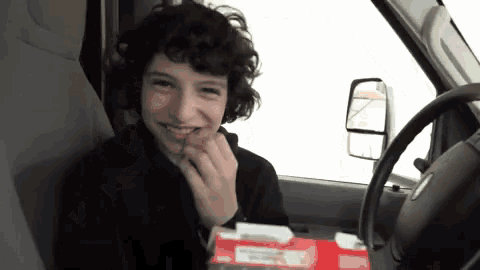 a young man is sitting in the driver 's seat of a ford van
