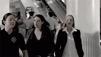 a group of women are walking down an escalator in a shopping mall .