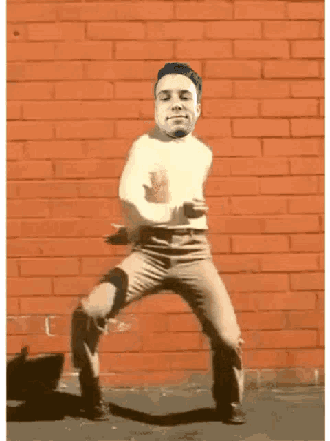 a man is dancing in front of a brick wall