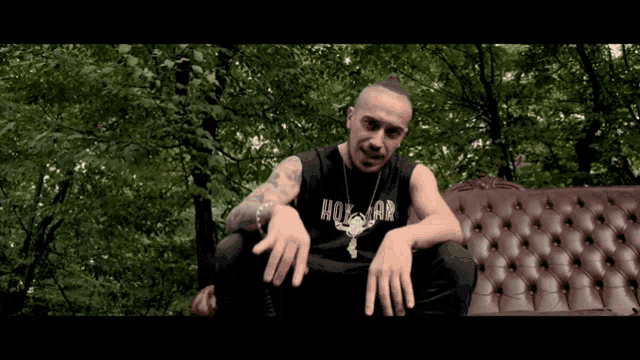 a man is sitting on a couch wearing a shirt that says hox ar