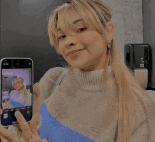 a woman taking a picture of herself with a phone
