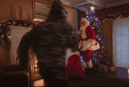 a man in a santa suit is standing in front of a fireplace holding a christmas tree