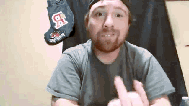 a man with a beard wearing a hat and a t-shirt with the letter b on it