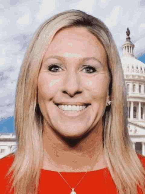 a woman in a red shirt smiles in front of the capitol building
