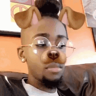 a man wearing glasses and a dog mask on his face is sitting on a couch .