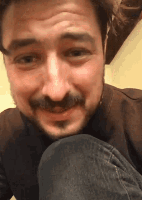 a man with a beard and mustache is smiling and looking down