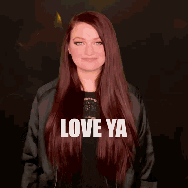 a woman with long red hair is wearing a black jacket and says love ya