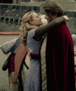 a man in a red cape and a woman in a purple dress are hugging each other