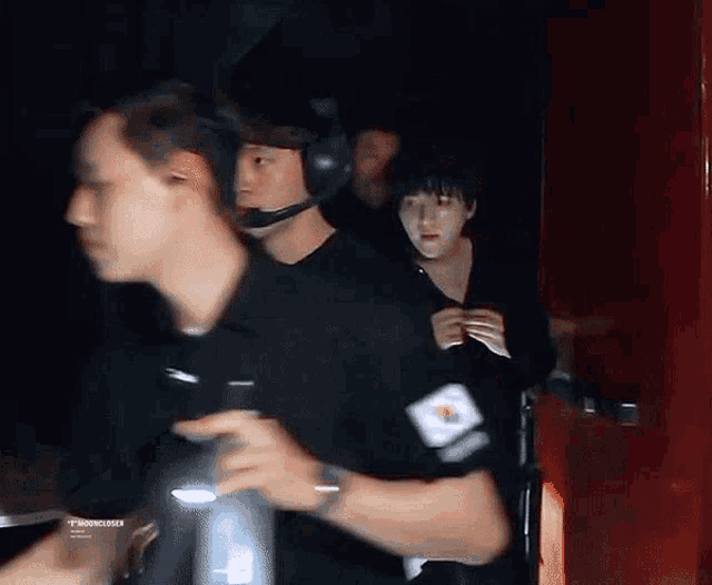 a group of people are walking in a dark room with a man wearing headphones .