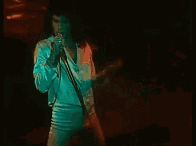 a woman is singing into a microphone on stage .
