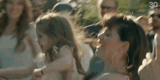a group of people are dancing in a park while a woman holds a little girl .