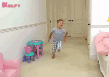 a child is running in a hallway with the word kulfy written on the wall behind him