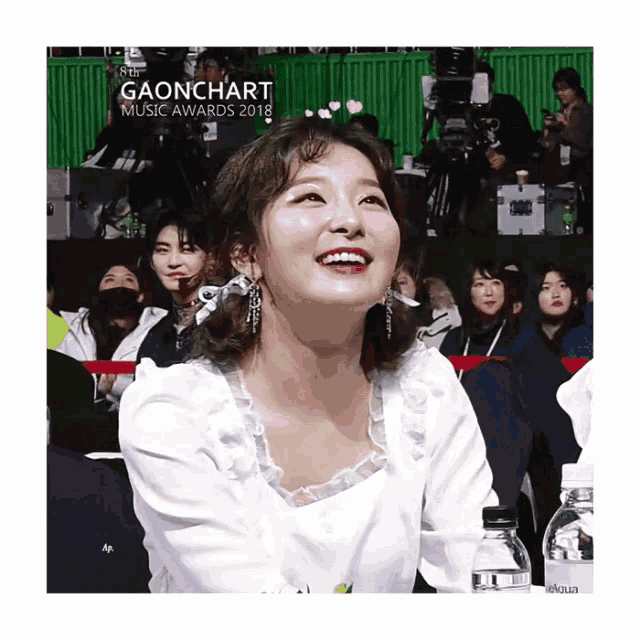 a woman is smiling in front of a sign that says gaonchart music awards