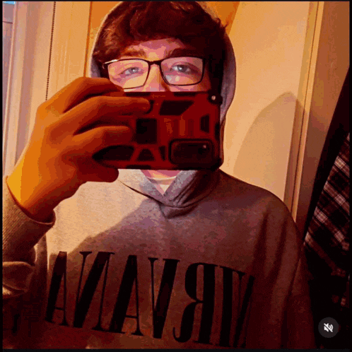 a young man taking a selfie with a nirvana hoodie on
