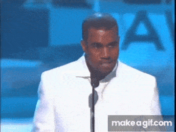 a man in a white suit is standing in front of a microphone at a podium .
