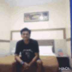 a blurry image of a man sitting on a bed